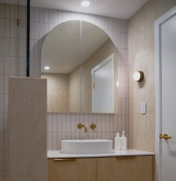 The Eterna Arch mirror cabinet above a light wood vanity, beside a round wall light